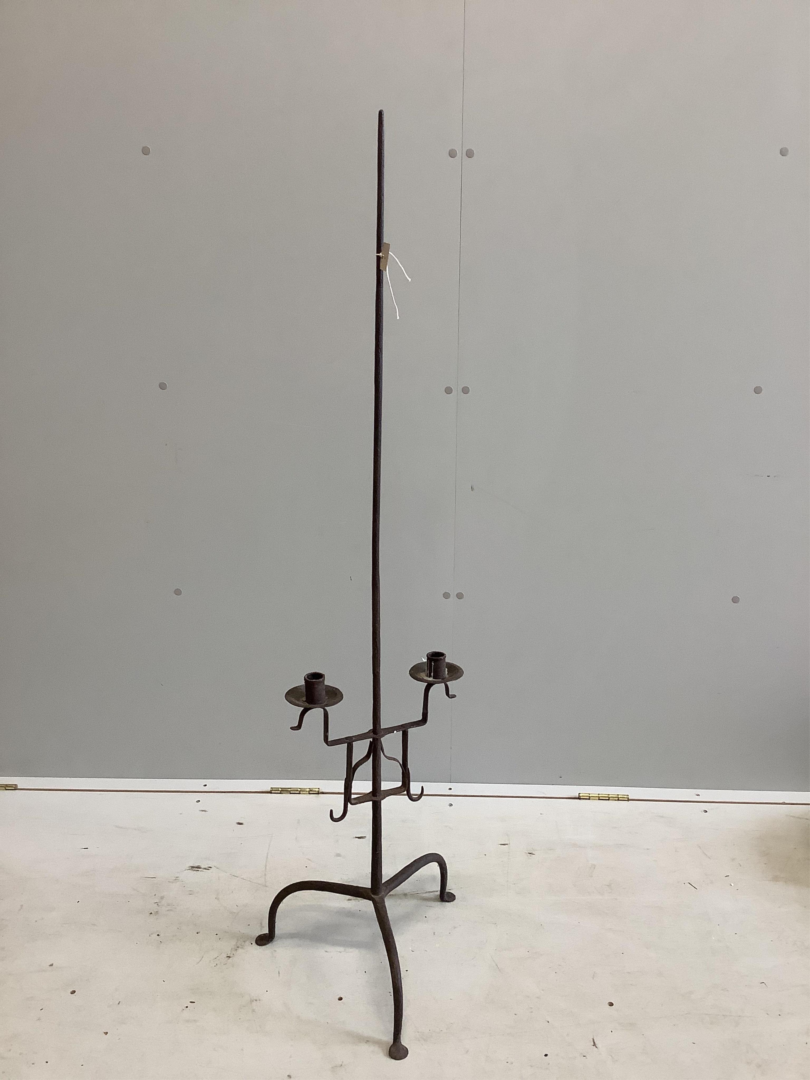 A 17th century wrought iron tripod candle stand, height 134cm. Condition - fair